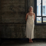 Front view of model wearing Aisling organic cotton long dress, showcasing soft flowy silhouette.Cream