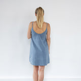 Back view of model showcasing Aisling short organic cotton dress and minimalist design. Naturally dyed in Indigo for sensitive skin