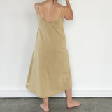 Back view of model wearing Aisling long organic cotton dress, highlighting low-back design and natural drape. Pomegranate