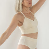 Front view of model wearing Branna organic cotton razorback bra, showing soft, supportive fit and wider strap. Natural cream for sensitive skin