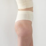 Side view highlighting the high-cut leg and snug waistline of the High Meara brief. Cream
