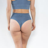 Back view of model in High Meara Brazilian brief, cheeky cut with smooth, comfortable fit. Indigo
