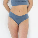 Model wearing the Meara Brazilian Brief in front profile. Soft, mid-rise fit in organic cotton. In Indigo