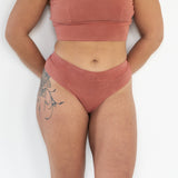 Model wearing the Meara Brazilian Brief in front profile. Soft, mid-rise fit in organic cotton. In Rubia colour.