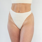 Model wearing High Skye organic cotton ribbed g-string, front view, showing high-cut fit and soft ribbed texture.