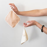 Little Brin cream and naturally dyed avocado organic cotton flannel hanging by its fabric loop, showcasing minimalist design and soft texture. Sustainable and friendly for sensitive skin