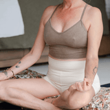 Front view of model in yoga pose wearing Lui organic cotton high-waist booty shorts in natural fabric.