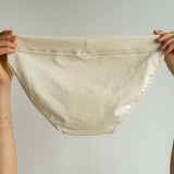 Back view of Tegan Full Bikini Brief in organic cotton, held up to reveal full back coverage and smooth, natural texture. Eco-friendly and gentle on skin.