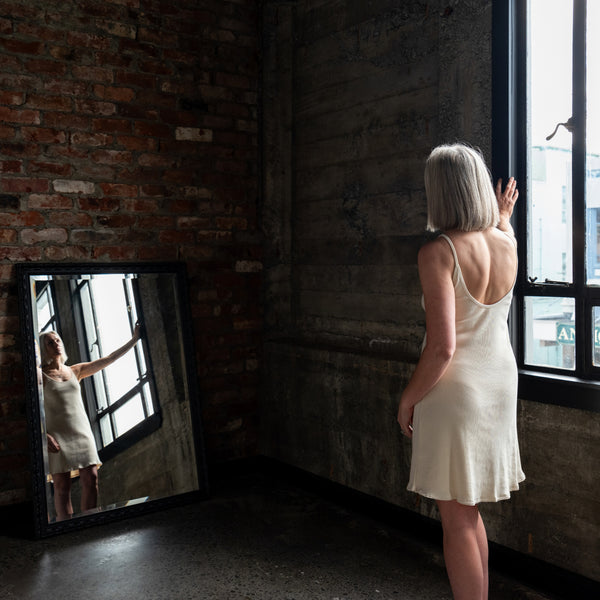Back view of model showcasing Aisling short ribbed organic cotton dress and minimalist design. Cream